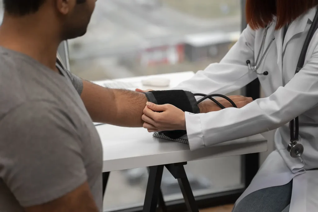 A doctor checking a patient's blood pressure, highlighting the connection between gum health and overall health, and the importance of preventing gum disease.