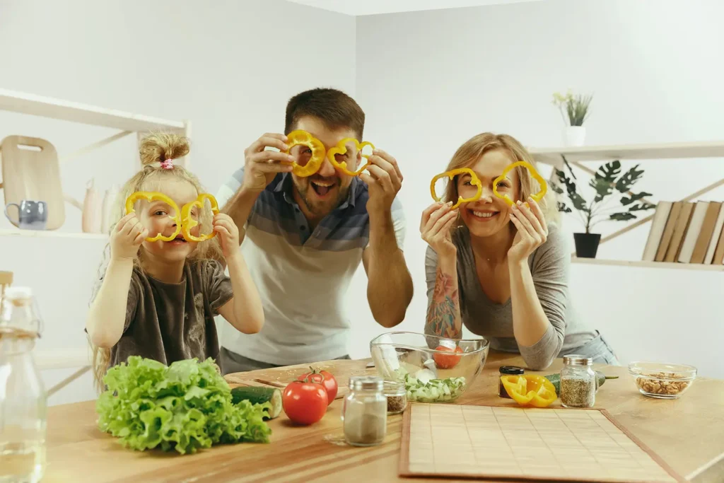 Happy family preparing a salad with nutrient-rich foods like bell peppers, promoting dental health through a healthy diet.