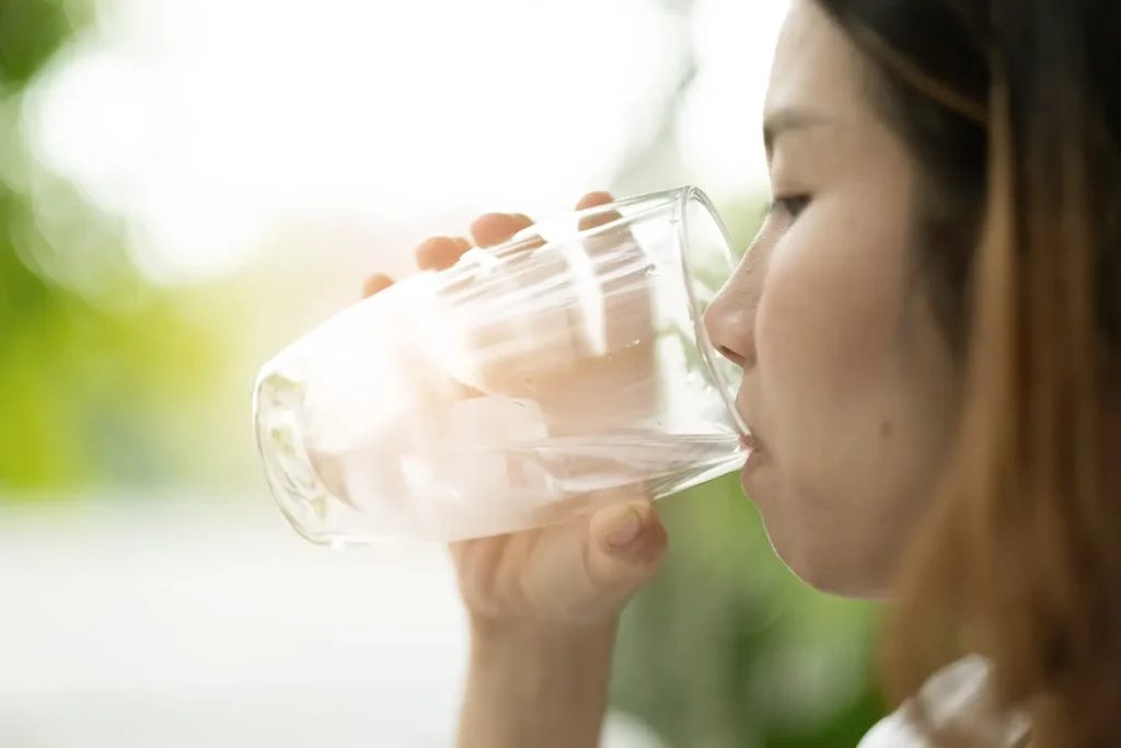 Woman drinking water to complement a diet of nutrient-rich foods, promoting dental health and overall well-being.