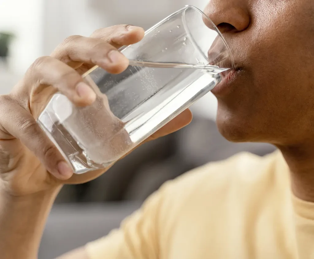 Man drinking a glass of water to alleviate dry mouth caused by allergies, promoting better oral health