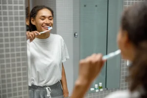 Woman practicing good dental hygiene by brushing her teeth as part of her daily routine, emphasizing the importance of preventative care, with guidance from Family Dental Group.